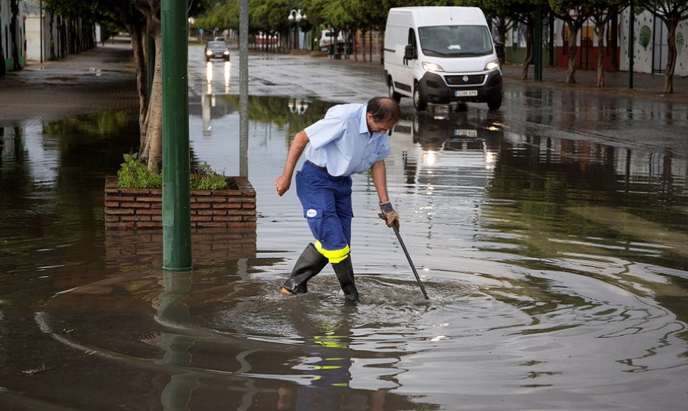 Un trabajador achicando el agua en mitad de la acera en Málaga./EFE