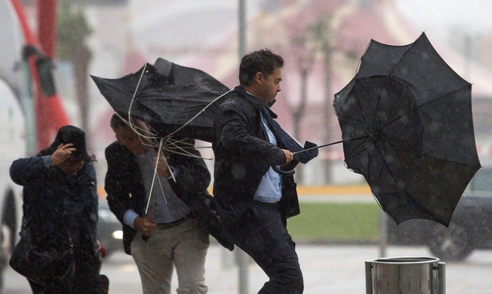 La gente sufriendo el mal tiempo en Málaga y peleándose con sus paraguas./ EFE