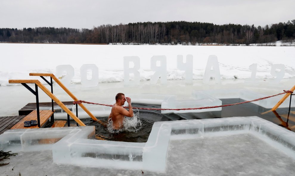 Un hombre toma un baño en las aguas heladas de un lago en la víspera de la Epifanía Ortodoxa cerca del pueblo de Pilnitsa, Bielorrusia.- REUTERS / Vasily Fedosenko