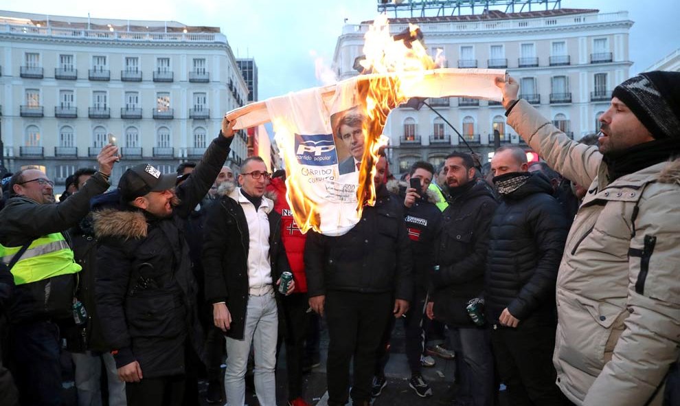 Los taxistas queman un cartel del PP con la cara del presidente de la Comunidad de Madrid en  segundo día consecutivo en la madrileña Puerta del Sol. (KIKO HUESCA | EFE)