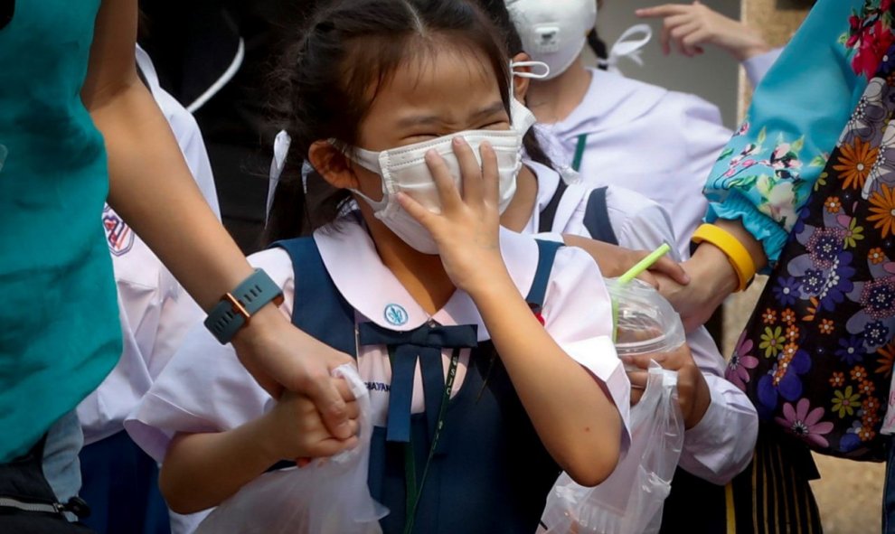 Una niña tailandesa aprieta la mascarilla que utiliza para protegerse de la contaminación en Bangkok. / EFE