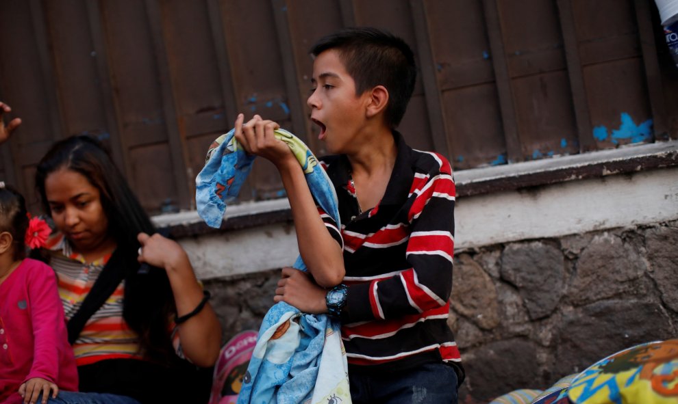 Un niño hondureño bosteza después de dormir en el suelo mientras espera en la fila para ingresar a la Comisión Mexicana de Asistencia para Refugiados (COMAR). / Reuters