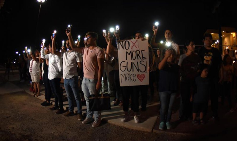 Decenas de personas oran este sábado, en la línea fronteriza de Ciudad Juárez (México), tras el tiroteo en un centro comercial de El Paso. EFE/ Rey Jauregui