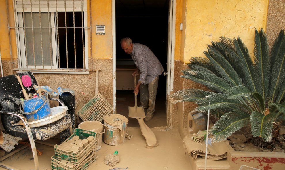 Un hombre elimina el lodo acumulado por las lluvias torrenciales en su casa de Orihuela, Alicante.- JON NAZCA / REUTERS