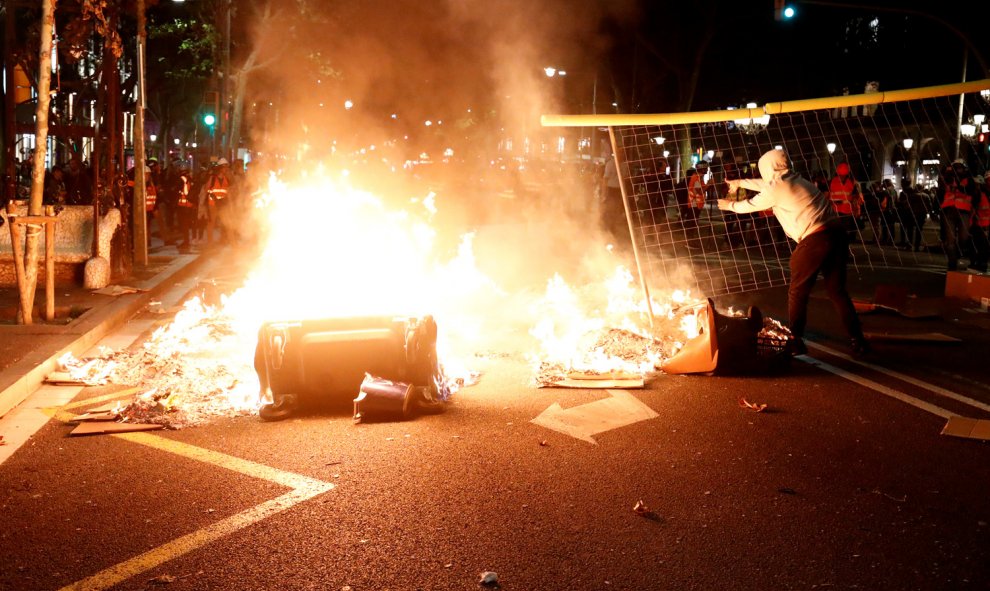 Un manifestante lanza una valla al fuego de una barricada en el Paseo de Gràcia en Barcelona durante los disturbios tras las concentración convocada por los CDR frente a la Jefatura Superior de Policía de Barcelona.- REUTERS/ALBERT GEA