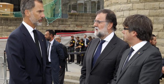 El rey de Felipe VI hablando con el presidente del Gobierno, Mariano Rajoy, y el presidente de la Generalitat de Cataluña, Carles Puigdemont, a su llegada a la basílica de la Sagrada Familia donde se celebró la Misa por la Paz en memoria de las víctimas d