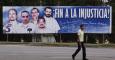 Un hombre camina frente a una valla con la imagen del llamado grupo de "Los Cinco"  en La Hablana. EFE