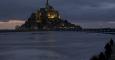 La gente se sienta en un terraplén para observar como la marea  rodea la abadía de Mont Saint-Michel, del siglo XI,en Normandía. REUTERS / Pascal Rossignol