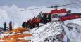 Una persona herida es subida a un helicóptero de rescate en el campamento base del Everest mientras los cadáveres de montañeros esperan ser trasladados, envueltos en sacos naranja.- AFP PHOTO / ROBERTO SCHMIDT