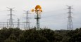 Un molino de viento cerca de unas torres eléctricas de alta tensión en la localidad madrileña de Galapagar. REUTERS