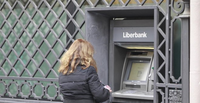 Una mujer opera un cajero automático en una oficina de Liberbank. E.P.