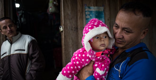 Un guerrillero sostiene en brazo a su hija de pocos meses en el campamento para desmovilizados de las FARC en La Fila, región de Tolima.-JAIRO VARGAS