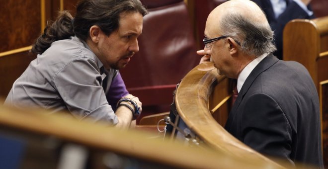 El ministro de Hacienda, Cristóbal Montoro, conversa con el líder de Podemos, Pablo Iglesias, durante un Pleno del  Congreso de los Diputados. EFE/Javier Lizón