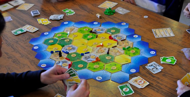 Varias personas juegan una partida al famoso Catan.