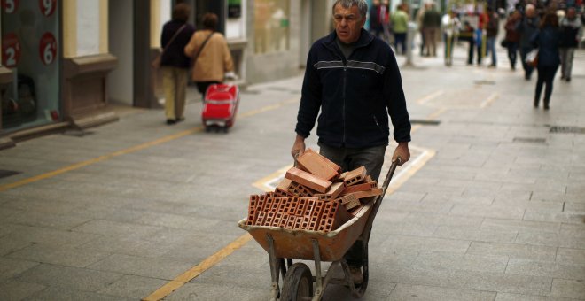 Un trabajador empuja una carretilla con ladrillos. REUTERS