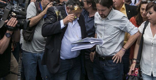 Julio Sanz,iz, presidente de la Federación Profesional del Taxi, recibe el impacto de un huevo en la cabeza mientras conversa con el líder de Podemos, Pablo Iglesias,c-d., en las proximidades de la plaza de Neptuno donde hoy el gremio de los taxistas madr