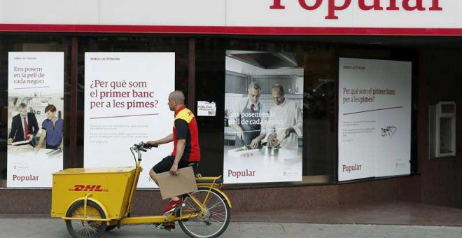 Un repartidor pasa ante una oficina del Banco Popular en el Paseo de Gracia esquina con la calle Aragón de Barcelona. | ANDREU DALMAU (EFE)