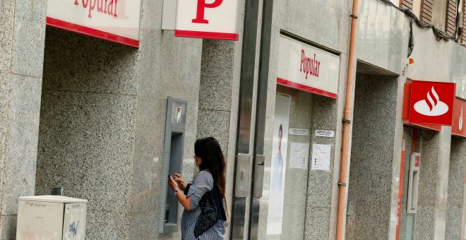 Una mujer saca dinero en un cajero de una entidad del Banco Popular que si sitúa junto a otra del banco Santander.REUTERS/Albert Gea