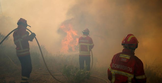 Tres bomberos trabajan para apagar las llamas en el bosque de Capelo, cerca de Gois. | RAFAEL MARCHANTE (EFE)