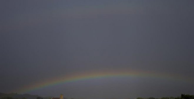 Vista de un arco iris sobre el cielo negro de San Sebastián, donde aún este viernes se mantiene la alerta amarilla por fenómenos costeros. | EFE