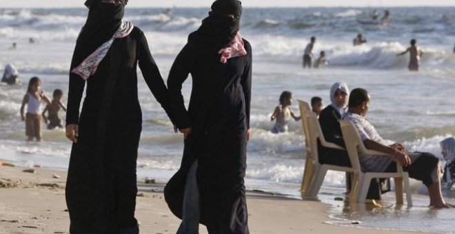 Dos mujeres con velo islámico en una playa.