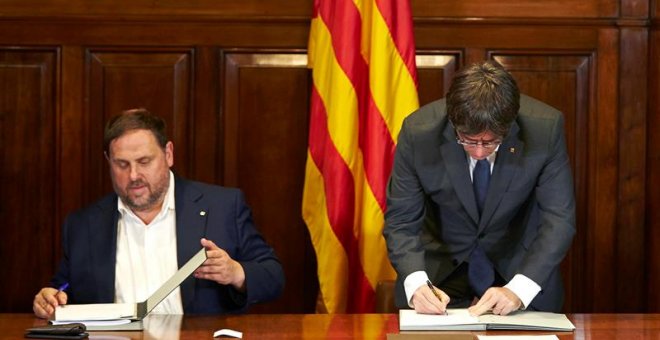 El presidente de la Generalitat, Carles Puigdemont, acompañado por el vicepresidente Oriol Junqueras, firma la convocatoria de referéndum. - EFE