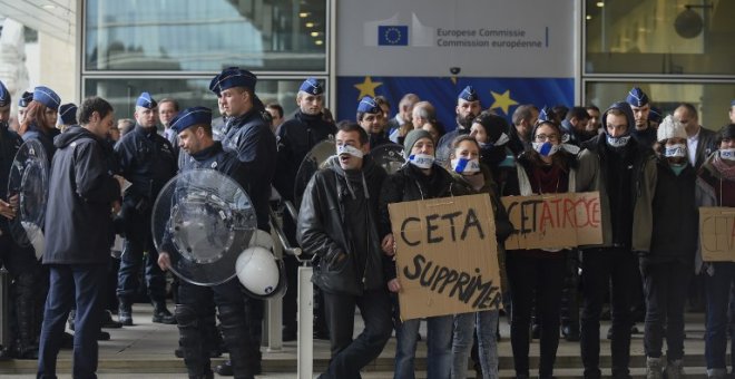 Policías belgas vigilan a los manifestantes concentrados frente al edificio de la Comisión Europea, durante la cumbre UE_canadá de octubre de 2016 en la que se firmó el CETA. AFP/jOHN tHYS