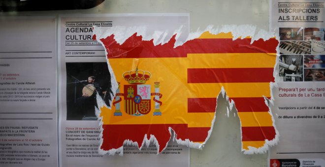 Una pegatina dañada de la bandera española junto a la catalana en una pared. / Reuters