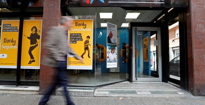 Un hombre pasa junto a una sucursal de Caixabank en Barcelona. REUTERS/Yves Herman