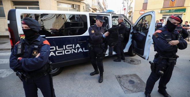 Mossos d'Esquadra protegen a agentes de la Policía Nacional cuando entran en los vehículos policiales frente a su hotel en Pineda de Mar, Barcelona. / Reuters