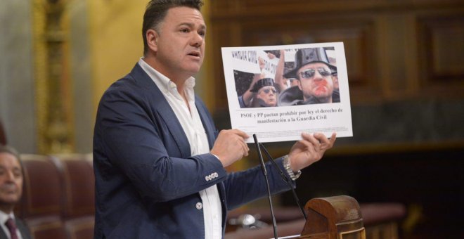 Juan Antonio Delgado, en la tribuna del Congreso, muestra una imagen de denuncia del pacto entre PP y PSOE en 2011 para negar a los guardias civiles el derecho de manifestación.