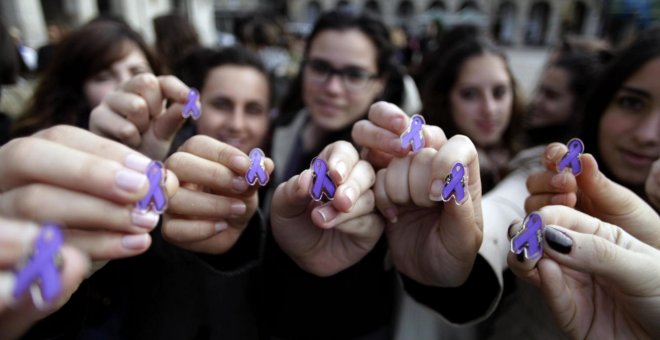 Varias jóvenes muestran lazos de color violeta, que simbolizan la lucha contra la violencia machista. (EFE)