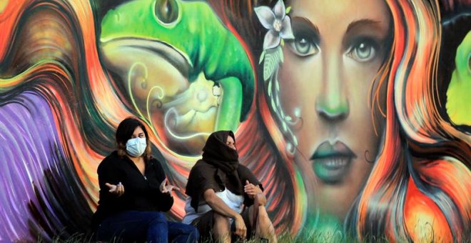 Dos mujeres cubren sus rostros debido a los gases lacrimógenos de un enfrentamiento entre manifestantes y la policía este viernes en Tegucigalpa (Honduras). EFE/Gustavo Amador