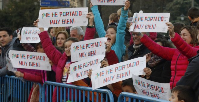 Niños disfrutando de la cabalgata de Reyes en Madrid con pancartas. EFE