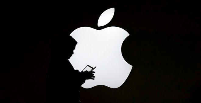 Una mujer mira el móvil enfrente de un logo de Apple en una tienda de la compañía situada en Shanghai, China. REUTERS/Aly Song/Archivo