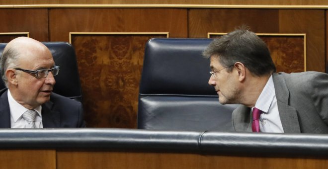 El ministro de Hacienda, Cristóbal Montero, conversa con el ministro de Justicia, Rafael Catalá, durante el Pleno del Congreso de los Diputados. EFE/ Fernando Alvarado