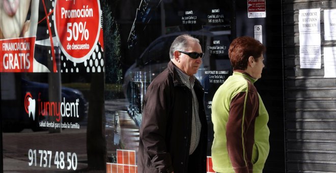 Dos personas leen los avisos dejados a los pacientes en la clínica Funnydent de Torrejón de Ardoz. EFE/Chema Moya