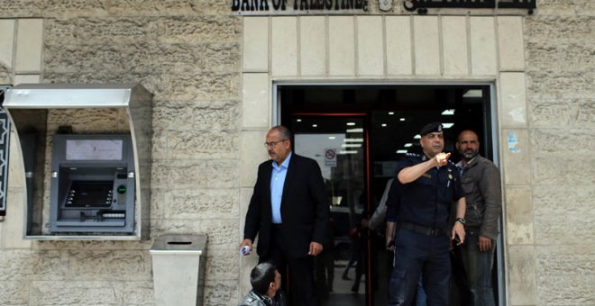 Un policía de Hamás gesticula ante la entrada de un banco en la ciudad de Gaza. | (REUTERS/Ibraheem Abu Mustafa)