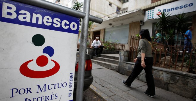 Una mujer camina junto a una sucursal del banco Banesco en Caracas. REUTERS/Carlos Garcia Rawlins