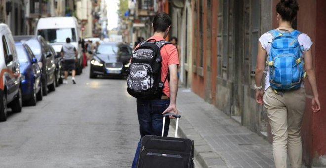 Dos personas con una maleta caminan por la calle. EFE