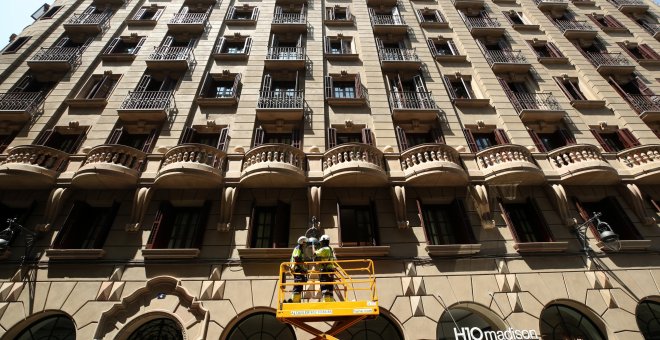 Unos trabajadores sobre una plataforma colocan una luz en una farola en Barcelona. REUTERS/Albert Gea