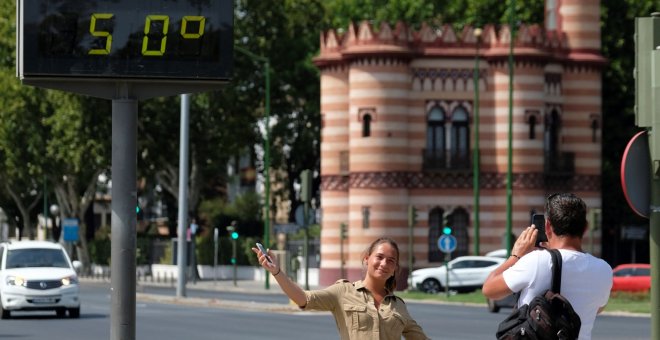 Una turista se fotografía bajo un termómetro que marca 50ºC hoy en Sevilla. EFE/Pepo Herrera