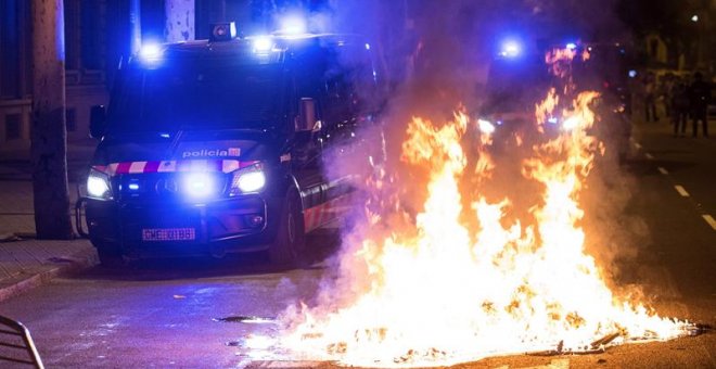 Un furgón de los Mossos d'Esquadra pasa junto al fuego durante los altercados al finalizar la movilización convocada por la ANC y otras entidades soberanistas. - EFE