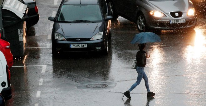 Una persona se protege de la lluvia con un paraguas durante la mañana de este viernes en la que el cielo de la Comunidad Valenciana permanece cubierto con precipitaciones fuertes o muy fuertes, sobre todo en Castellón y Valencia - EFE/Kai Försterling