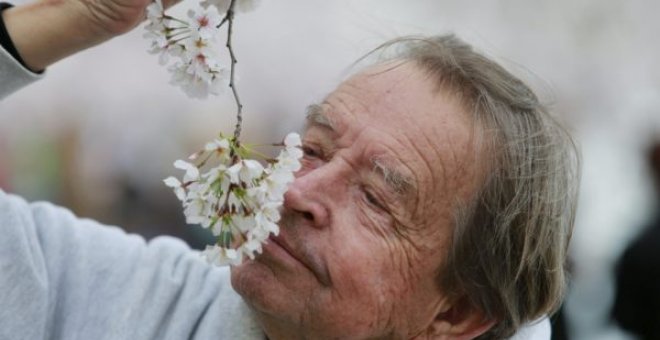 Un hombre oliendo una flor./REUTERS