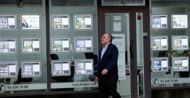 Un hombre pasa por delante de una oficina de una inmobiliaria en Barcelona. REUTERS/Albert Gea