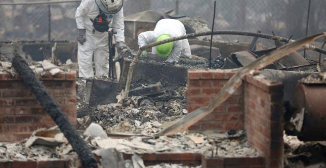 Miembros de un equipo de rescate buscan restos humanos en una de las miles de casas quemadas en California. (TERRAY SILVESTER)