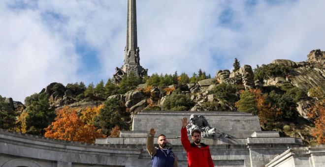 Dos jóvenes realizan el saludo fascista delante de la entrada principal del Valle de los Caídos. (SUSANA  VERA | REUTERS)