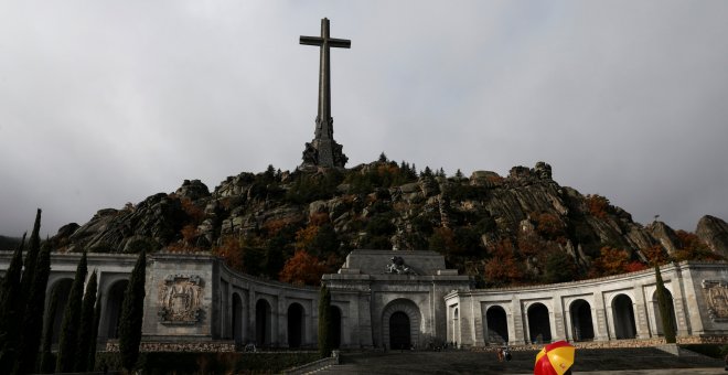 Un hombre con un paraguas con los colores de la bandera española en la explanada de la Basílica del Valle de los Caidos. REUTERS/Susana Vera