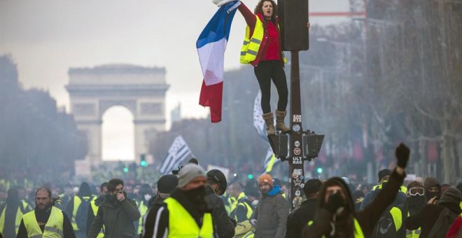 Una mujer grita consignas subida a un semáforo durante una protesta en los Campos Elíseos en París (Francia) hoy, 24 de noviembre de 2018. El ministro francés del Interior, Christophe Castaner, culpó hoy a la ultraderecha y a su líder, Marine Le Pen, de l